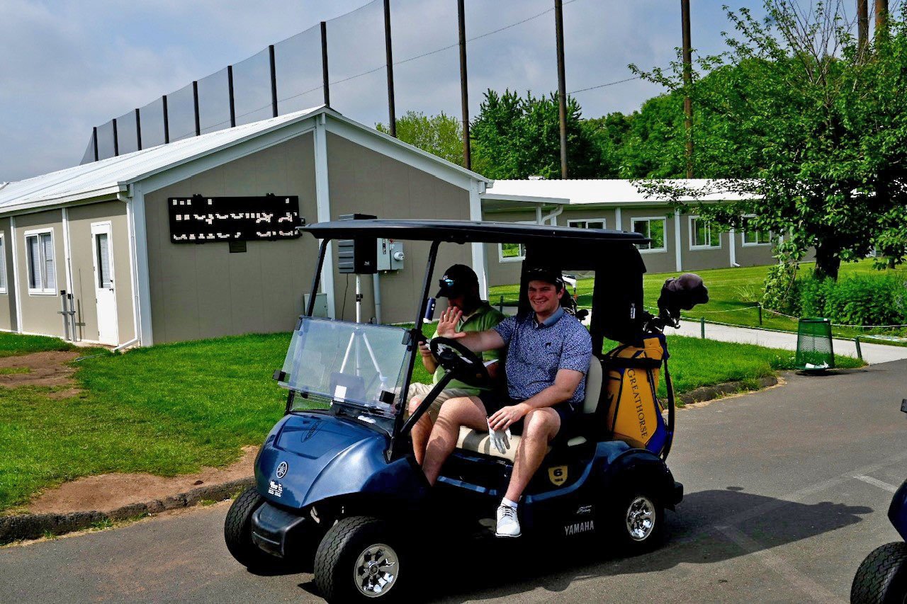 Two individuals driving in a golf cart